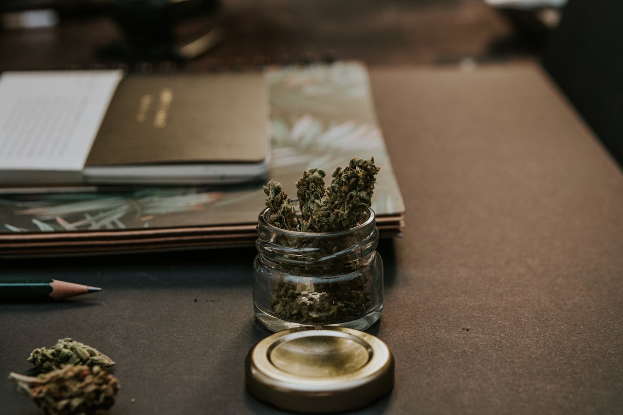 services-06 A close-up image of cannabis buds in a glass container on a desk, emphasizing a natural and relaxed setting.